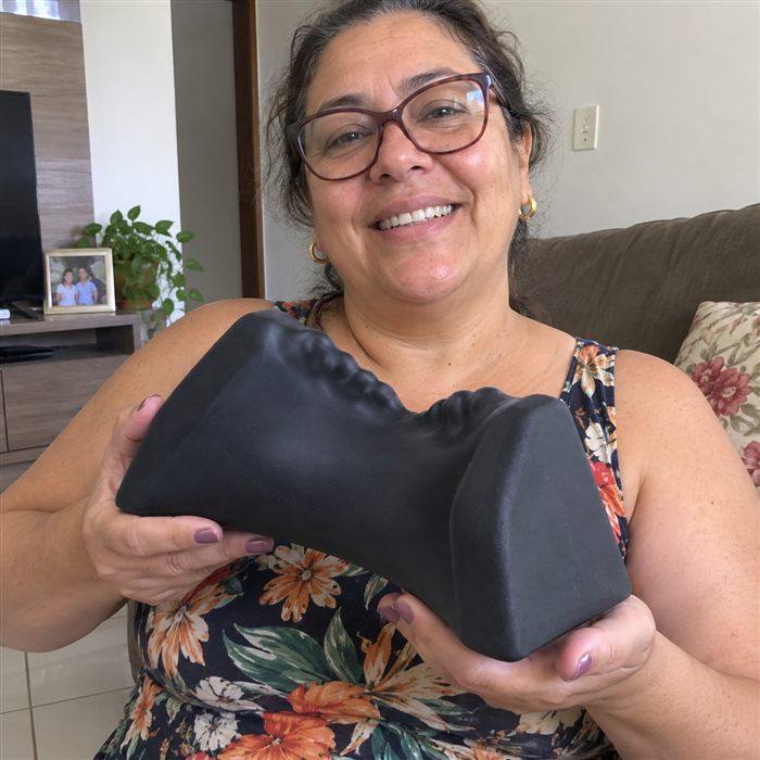 Maria das Graças sorrindo, segurando o Alívio Cervical Revertia
